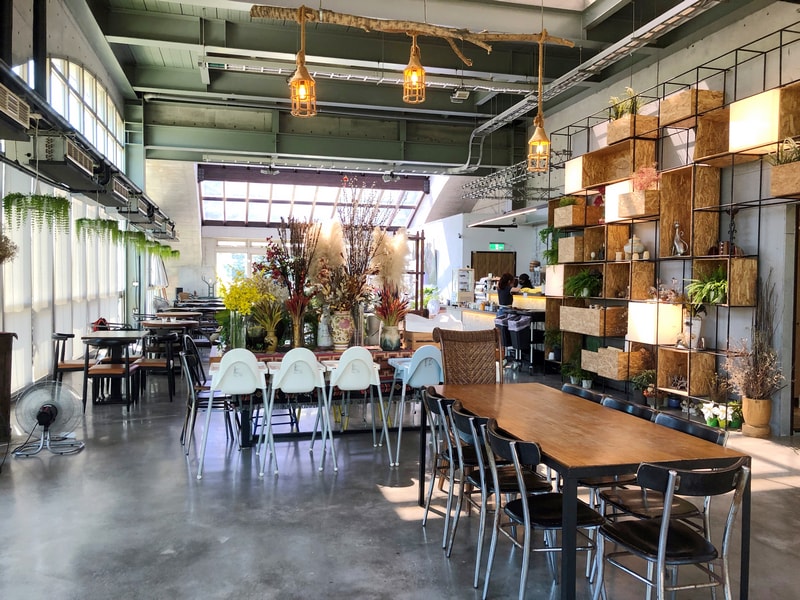 Arc Cafe 二樓空間，拱型窗撒入自然光，長桌擺放乾燥花與玻璃器皿，白色高腳椅展現親子友善設計。