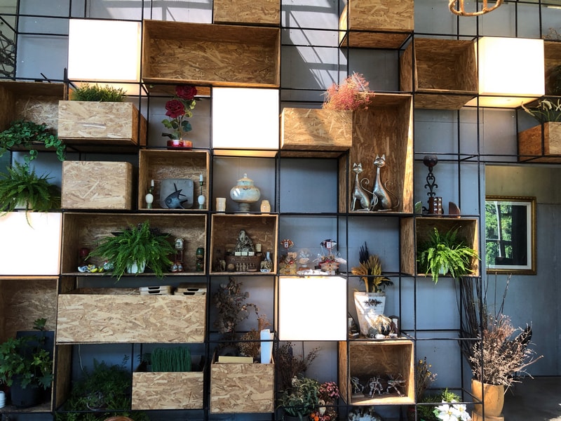 Arc Cafe二樓展示牆，由多個方格組成。擺放雕、陶器、書法、乾燥花與綠植。營造層次感與溫暖氛圍。