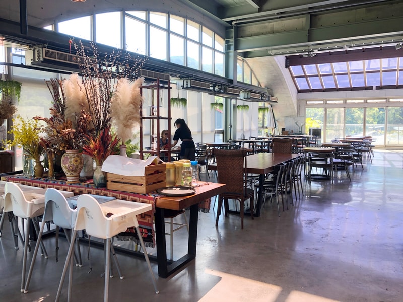 Arc Cafe 二樓空間，拱型窗撒入自然光，長桌擺放乾燥花與玻璃器皿，白色高腳椅展現親子友善設計。