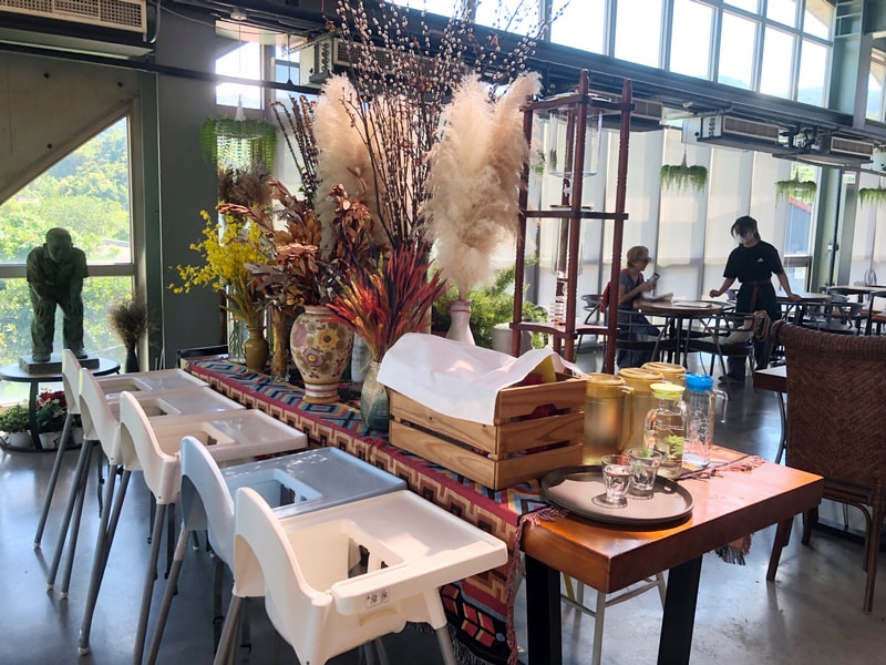 Arc Cafe 二樓空間，拱型窗撒入自然光，長桌擺放乾燥花與玻璃器皿，白色高腳椅展現親子友善設計。